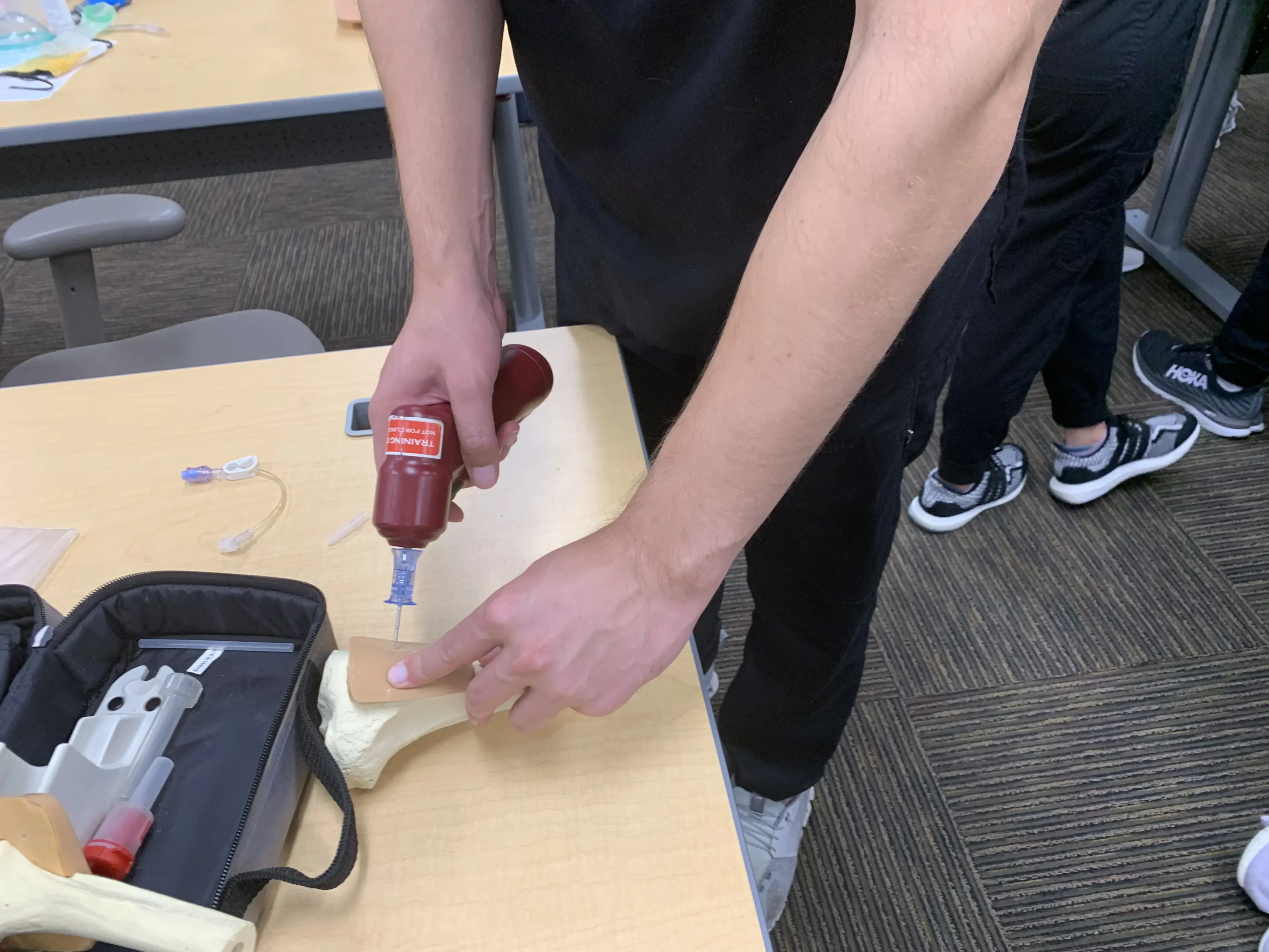 Person practicing medical drill on bone model